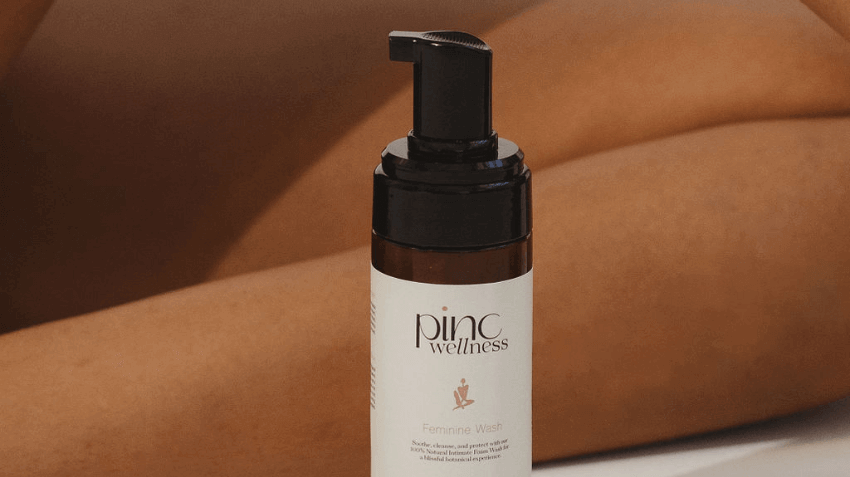 Close-up of a hand holding a boric acid suppository with soft candlelight in background