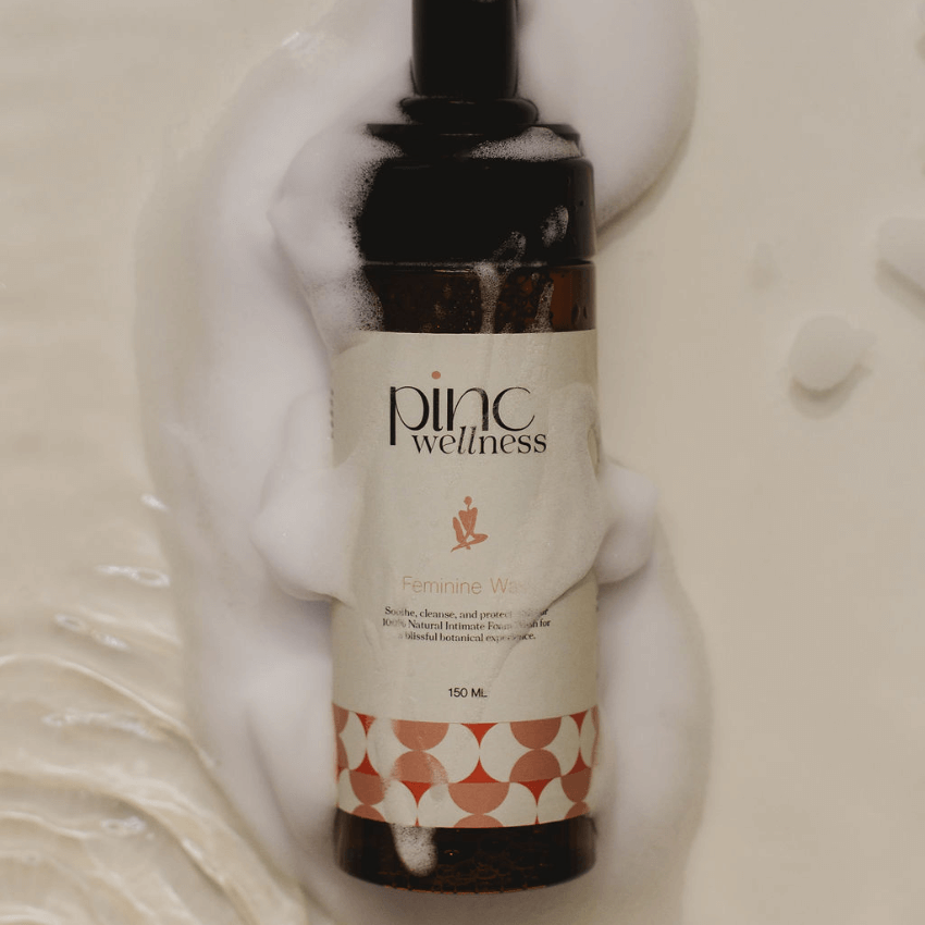 Feminine wash bottle with foamy bubbles on beige, fresh and soothing.