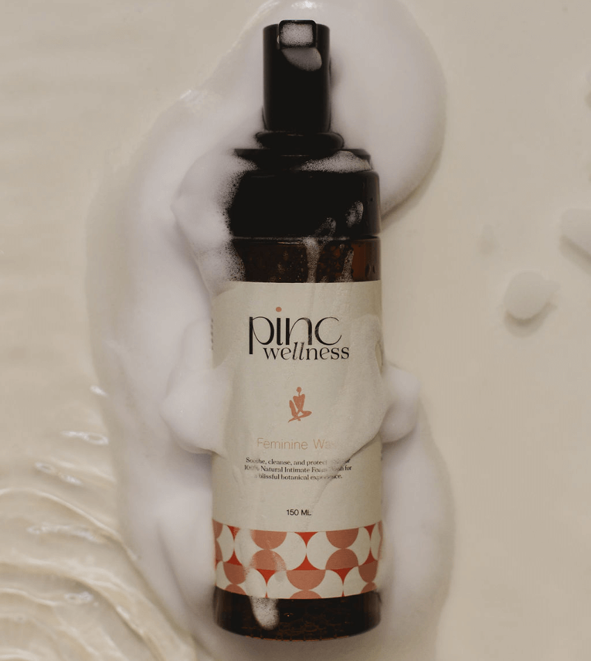Feminine wash bottle with foamy bubbles on beige, fresh and soothing.