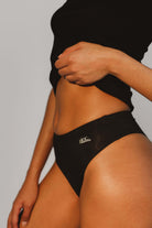 Person in black underwear showing fit figure, confident tone.