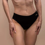 Close-up of toned midriff in black underwear, neutral background, confident.