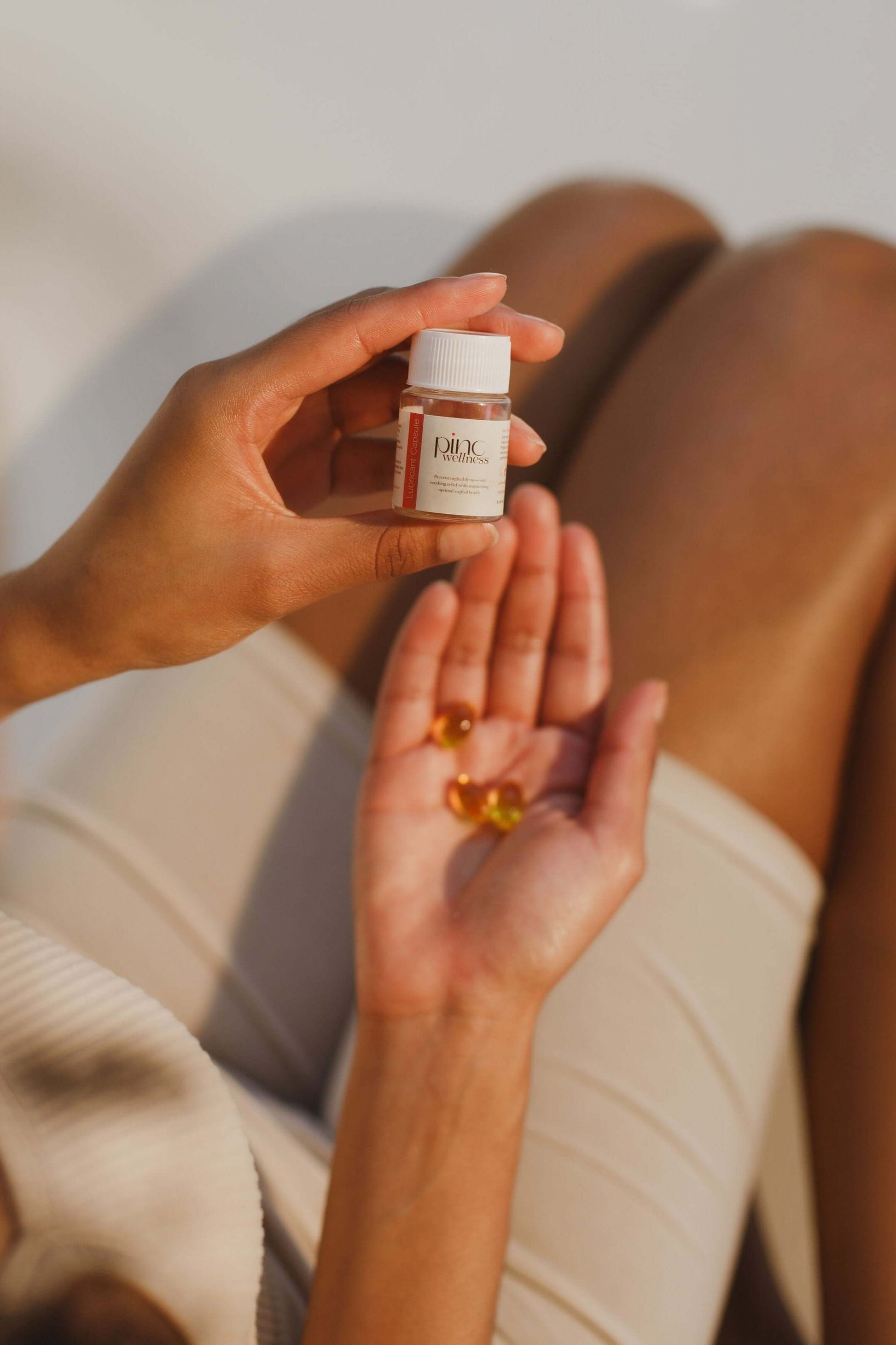 Person holding lubricant capsules bottle with capsules in hand for intimate hydration and comfort.