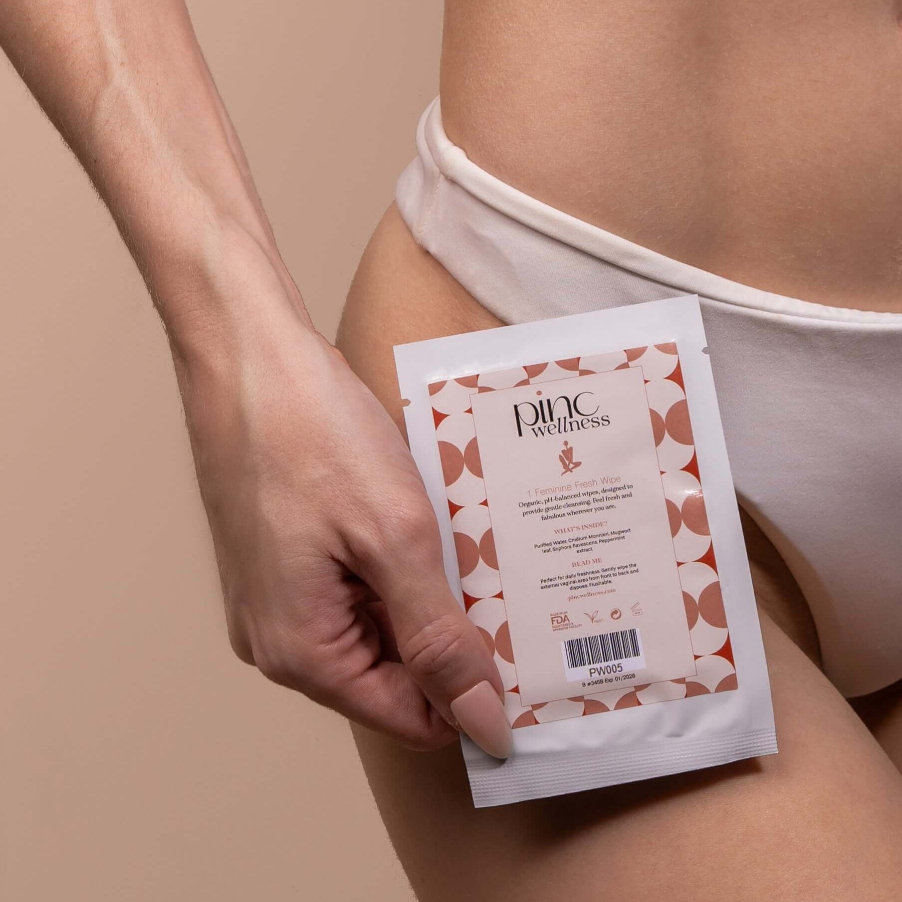 Person in white underwear holding Pinc Wellness packet on thigh, clean vibe.