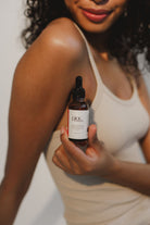 Woman in white singlet holding a bottle of Pinc Wellness Natural Lubricant