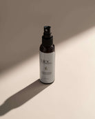 Dark Pinc Wellness spray bottle on light surface, long shadow, minimalist.