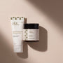 A white tube and a dark amber jar of Pinc Wellness lubricant products with a black lid, displayed on a warm beige background with soft diagonal shadows.