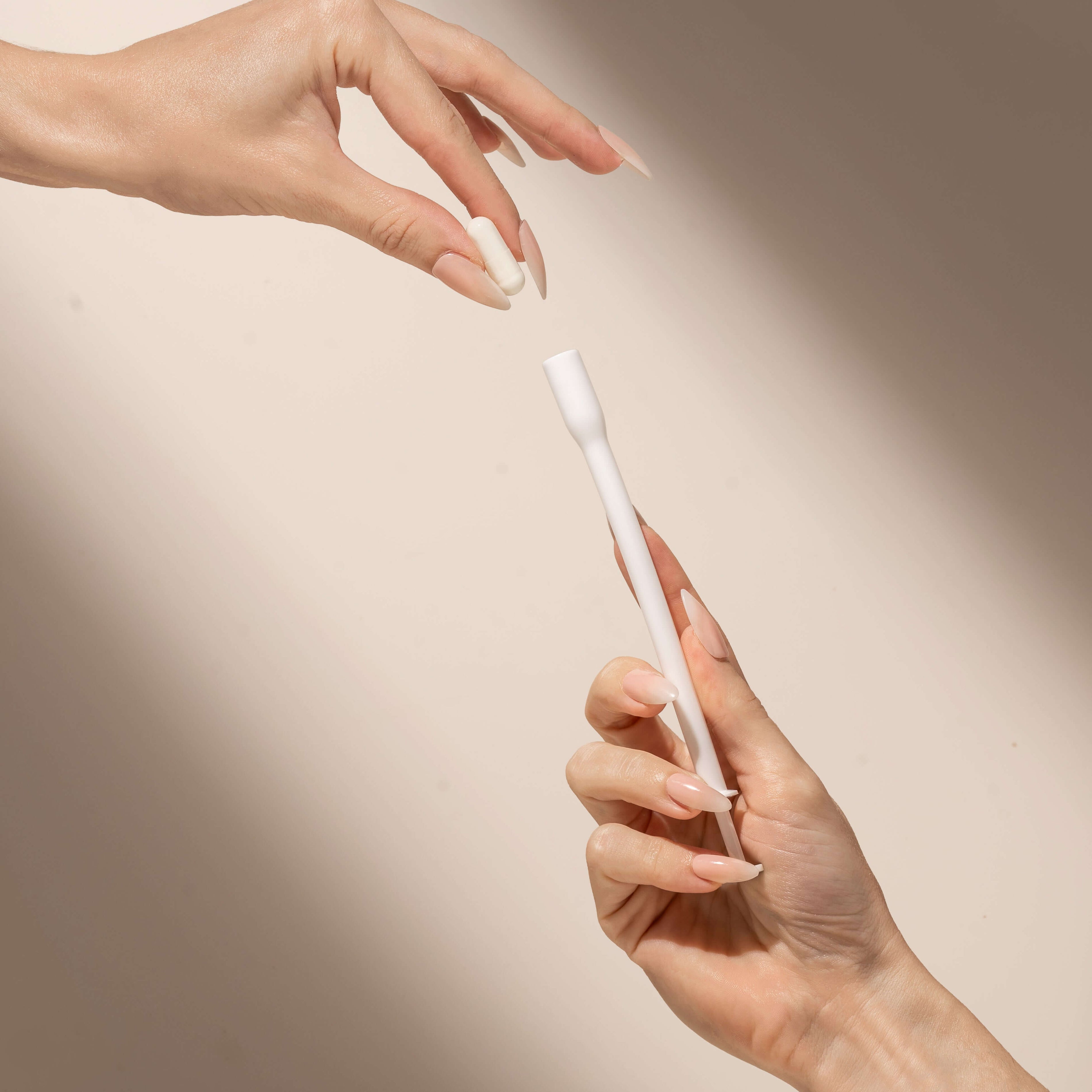 Two hands exchanging sleek white pen on neutral background, elegant minimalism.