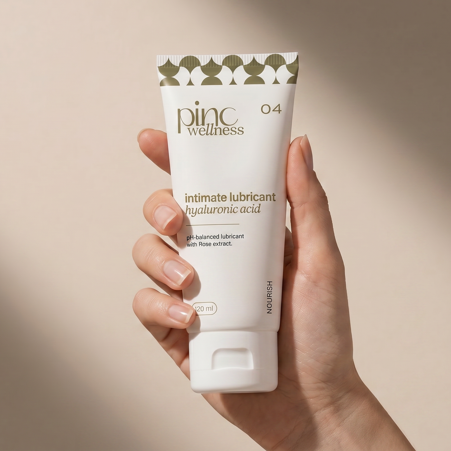 Hand holding a tube of intimate lubricant with a beige background