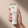 Hand holding a tube of intimate lubricant with a beige background